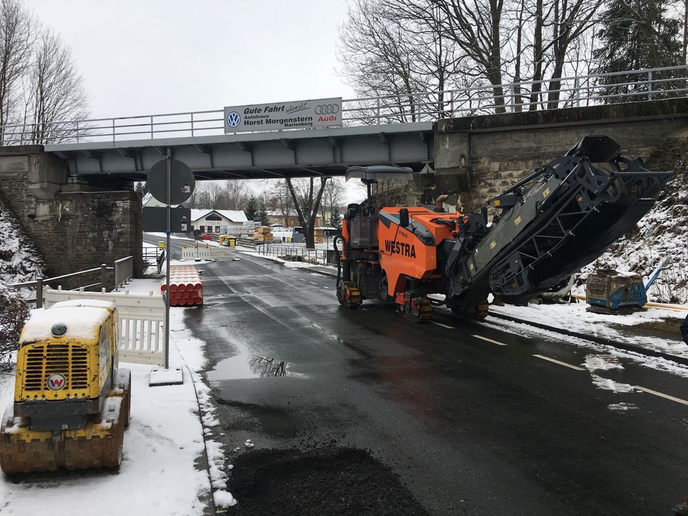 Asphaltfräse unter einer Eisenbahnbrücke